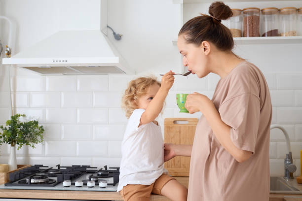 istock Brown haired woman with bun hairstyle having lunch with her infant while daughter drinking hot chocolate milk at table enjoying peaceful and nurturing moment at home 2175140965