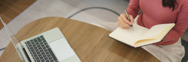 istock Young businesswoman thoughtful and taking notes in notebook while reading business data on laptop 2175143264