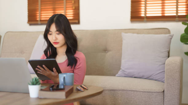 istock Young businesswoman reads business data on laptop and writing notes in tablet while working at home 2175143432