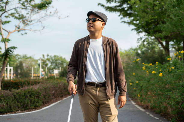 istock Young blind man walking in city with walking stick. Visually impaired man difficult to traveling on the road wearing sun glasses Cross the road cross the footbridge 2175143729