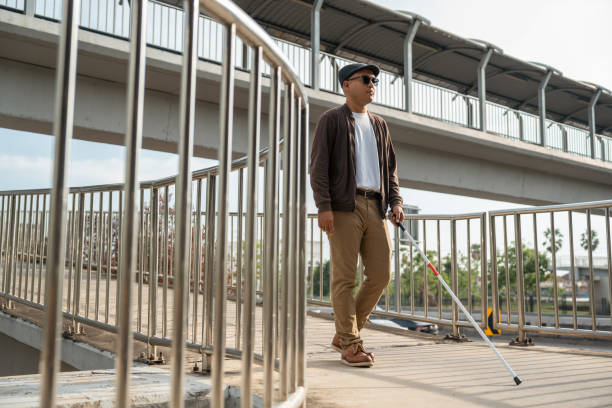 istock Young blind man walking in city with walking stick. Visually impaired man difficult to traveling on the road wearing sun glasses Cross the road cross the footbridge 2175147201