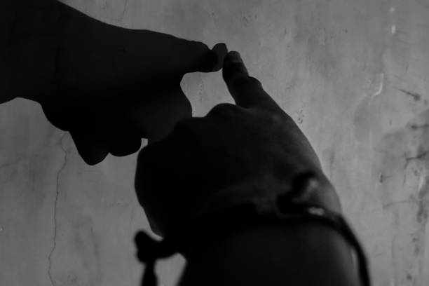 A person's hand touches his own shadow on a low light wall.
