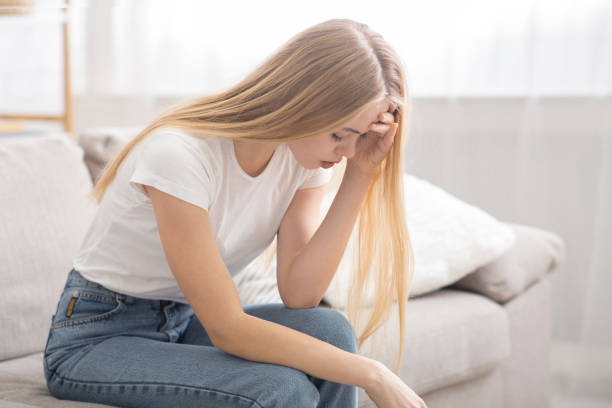 istock Depressed young girl sitting on couch at home alone 2175152952