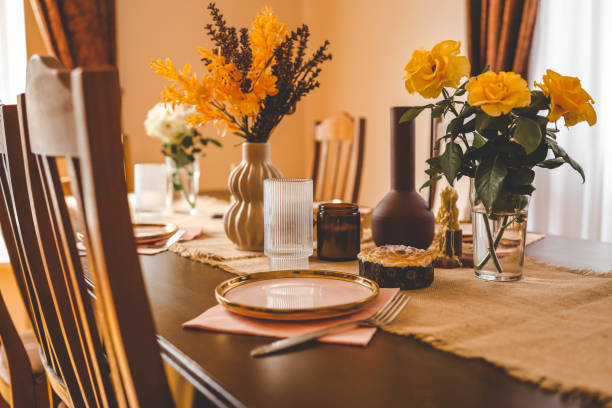 istock Beautiful table setting with a ceramic pink plate, a fork, and a glass of water on a rustic burlap tablecloth. Yellow roses, a decorative vase, and a pastry in the background create a cozy, warm atmosphere 2175153139