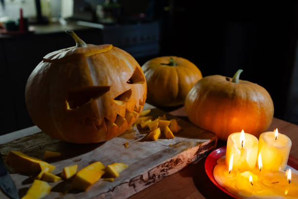 istock A carved pumpkin for halloween is on a cutting board beside candles 2175153893