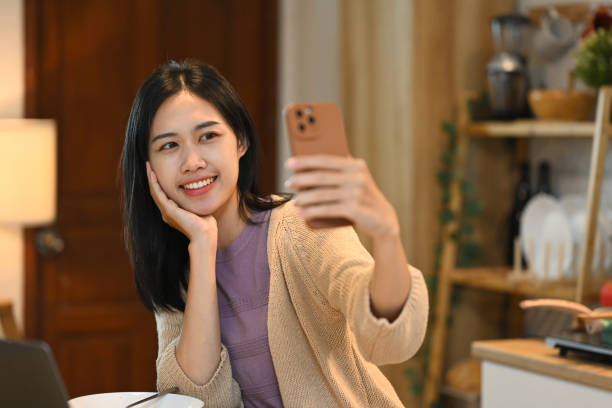 istock Beautiful young woman taking selfie with smartphone in the kitchen 2175155268