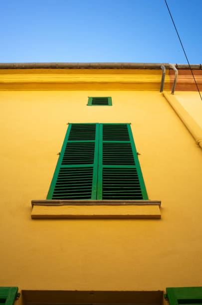 A yellow building with green shutters on the windows.