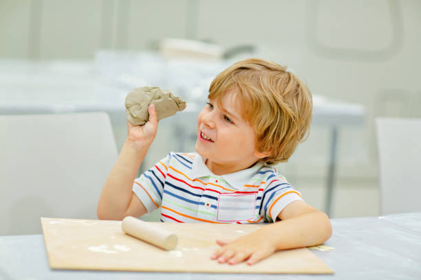 Little blond boy modeling with clay at master class art in a museum, indoors. Creative leisure for kids in kindergarden and at home, indoors.