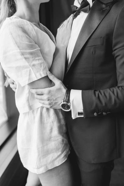 Strong hands wrap securely around a waist emphasizing the closeness and emotional bond shared between two people in this monochrome moment.