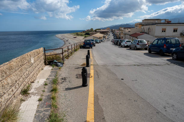 Messina, Italy - May 21, 2024: Industrial Zones and Vehicles Surround a Beach in Messina, Creating a Stark Contrast Between Natural Beauty and Urban Neglect.