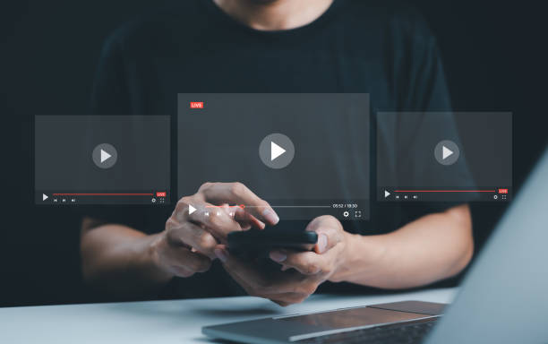 istock Live streaming and video content creation concept. A man uses a smartphone device with transparent video player interfaces, symbolizing live streaming, digital media, and video content creation. 2175194609