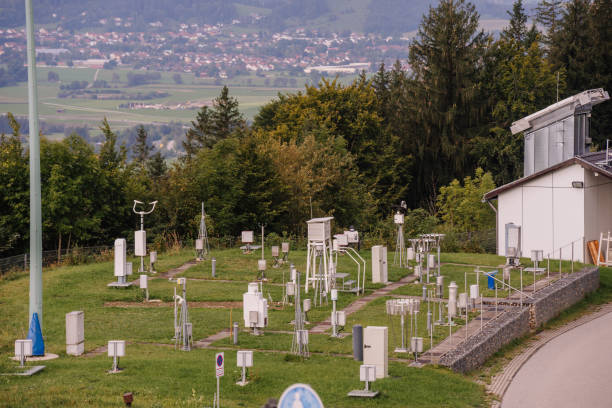 Bavaria, Germany - September 15, 2024 - A weather station in Bavaria with various meteorological instruments on a grassy field, with a village and hills in the background.