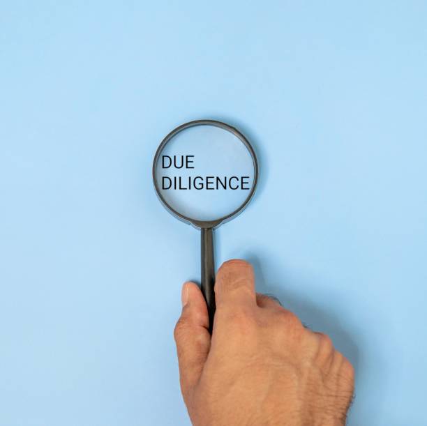 istock A hand holding a magnifying glass over the words DUE DILIGENCE on blue background. 2175198024