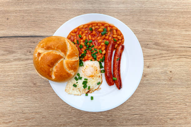 English breakfast with chives and fried eggs and beans in sauce lying flat on a plate.