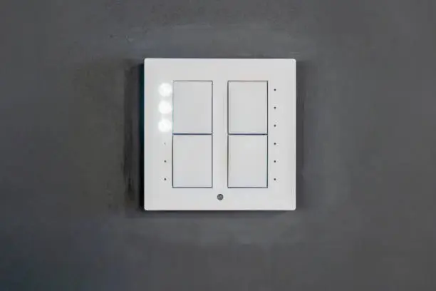 Photo of 4 button white modern smart light scene switch on a grey wall, object front view, frontal shot, building interior detail nobody Switching lighting scenes in a smart home setup multiple devices control