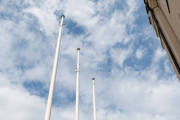 3 simple white empty flag poles outdoors, flagpoles outside the building, background, copy space, cloudy blue sky, white clouds, three empty flag posts masts template, nobody, no people, flags down