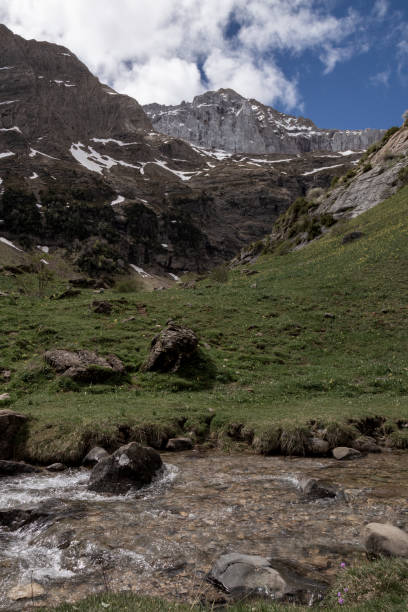 istock Majestic mountain landscape with a clear stream flowing through a lush green valley 2175237138