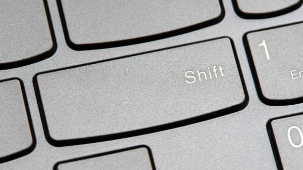 istock Man pressing the shift key on a modern laptop computer keyboard closeup top view, one person. Shift button key, shifting changing simple abstract concept, capital letters, special characters symbol 2175239796