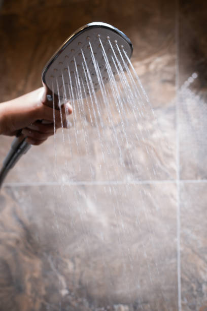 istock A woman's hand holds a shower head while taking a shower. 2175245027