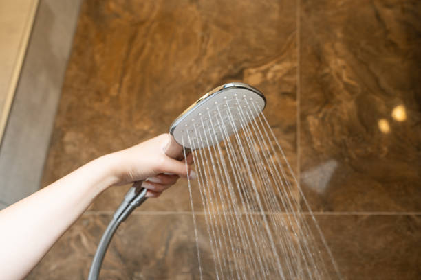 istock A woman's hand holds a shower head while taking a shower. 2175245115