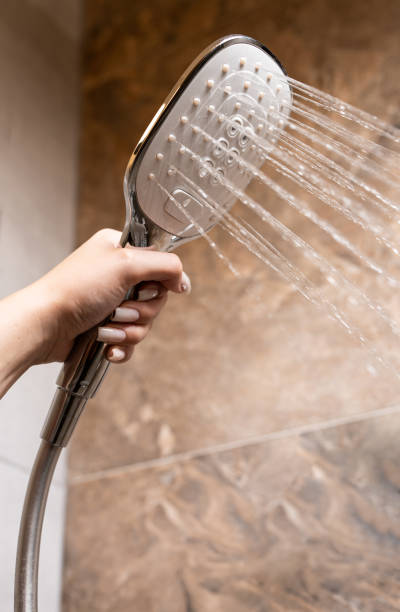 istock A woman's hand holds a shower head while taking a shower. 2175245166