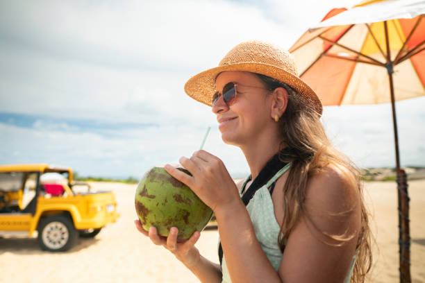 Tourist holding coconut water while looking at the beach in Rio Grande do Norte, Brasil