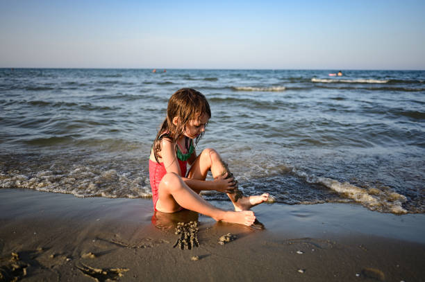 Little girl playing with dirt on a beach.