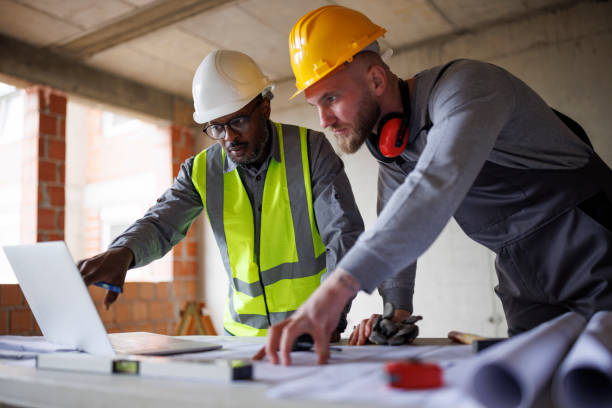 istock Architect and construction worker reviewing blueprints on laptop computer at the construction site 2175282036