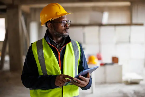 Portrait of male engineer with hardhat using digital tablet while working on construction site Portrait of male engineer with hardhat using digital tablet while working on construction site