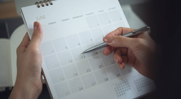 istock 2025 Calendar event planning timetable agenda plan on organize schedule. Event planner agenda organizing by organizer schedule. Business woman hand writing on calendar planner on office table, closeup 2175286446