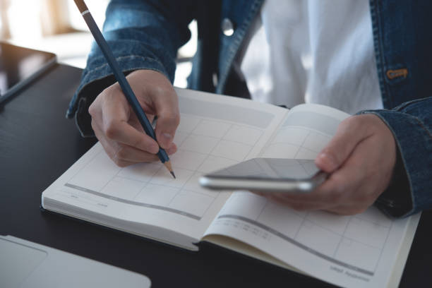istock Event planner timetable agenda plan on year 2025 schedule event. Business woman checking planner on mobile phone, taking note on calendar desk on office table. Calendar event plan, work planning, mockup 2175286448