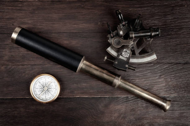 Retro vintage spyglass telescope with sextant on wooden background