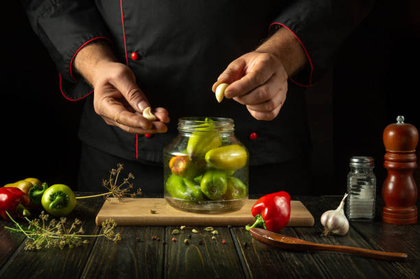 istock Preserving bell pepper on the kitchen table with garlic by the chef hands. Bell peppers in a jar with a delicious aromatic marinade 2175299013