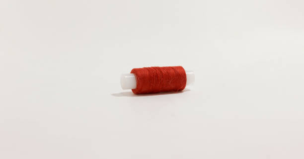 Close up of red thread spool on white background, perfect for sewing or crafting themes.