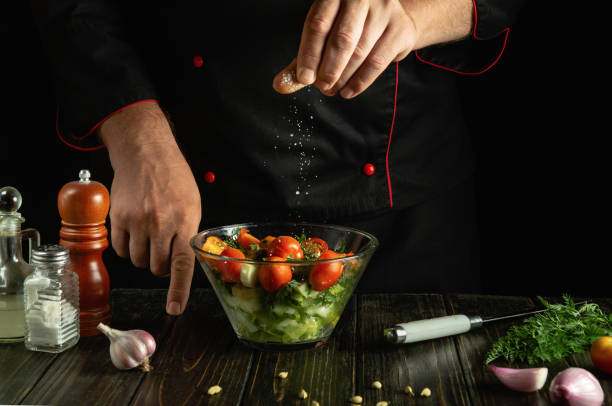 istock A cook at the kitchen table prepares a vegetable mixture for dinner. The chef adds salt to a vegetable salad with his hands. Vegetable diet menu for a restaurant or hotel 2175299163