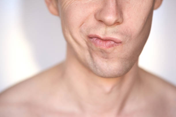 Caucasian man mouth with parted lips, visible white teeth, clean-shaven skin. Close up macro shot, unrecognizable person.