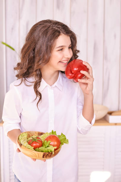istock Young girl enjoying fresh vegetables in a bright kitchen setting 2175300369