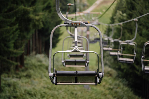 Bavaria, Germany - September 15, 2024 - Empty ski lift chairs suspended over a green hillside, surrounded by trees in a scenic mountainous area in Bavaria.