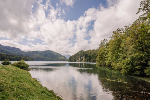 istock A peaceful lake surrounded by forested hills and mountains under a cloudy sky, reflecting the natural beauty of Bavaria, Germany. 2175301396