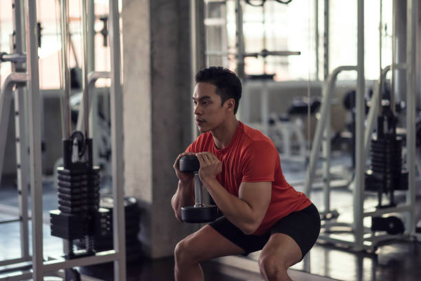 istock Asian muscular man biceps squat exercise by heavy dumbbell in gym 2175305074