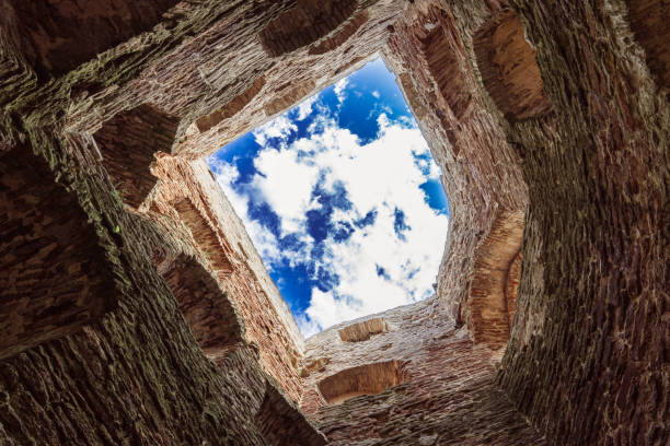 Looking up at a vibrant blue sky through an ancient stone opening.
