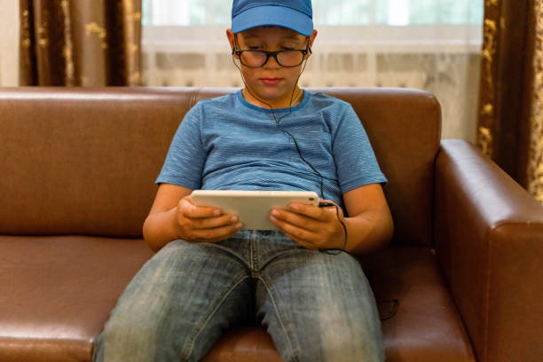 istock A young boy wearing a blue cap is focused on his tablet 2175307482