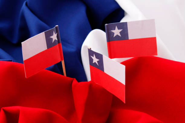 Three Chilean paper flags on red, white and blue fabric background