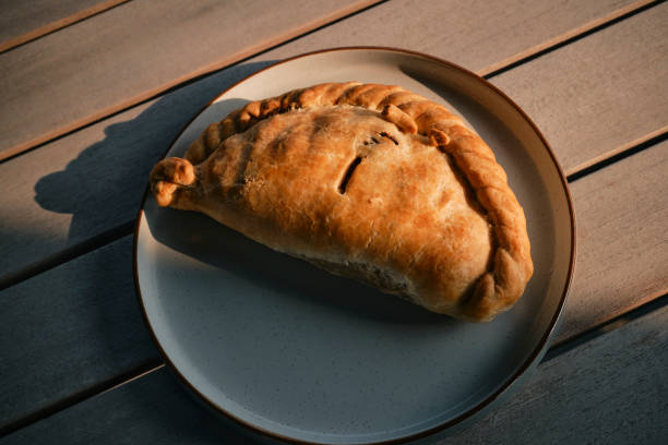 Overhead view of a traditional Cornish Pasty on a rustic plate in natural sunlight, photographed in Cornwall.