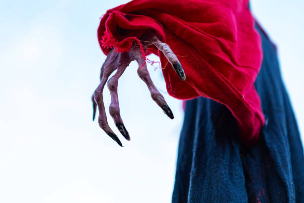 A chilling image featuring a scarecrows tattered red sleeve with a sinister, grimy hand and elongated black nails emerging from it. The unsettling angle further enhances the eerie atmosphere.
