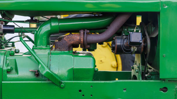 Tractor engine compartment displays intricate mechanical components. Green engine block with yellow accents showcases pipes, hoses, and various parts, demonstrating the complexity of modern agricultural machinery's power unit.