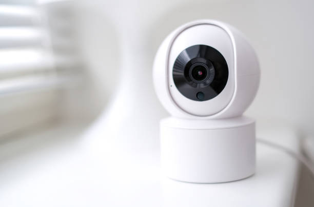 istock A white security camera with a black lens is mounted on a white surface. The camera is designed to capture images and record video footage 2175334376