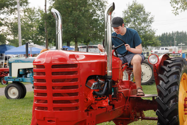 istock Autistic young man examines vintage tractor controls at country fair. 2175335170
