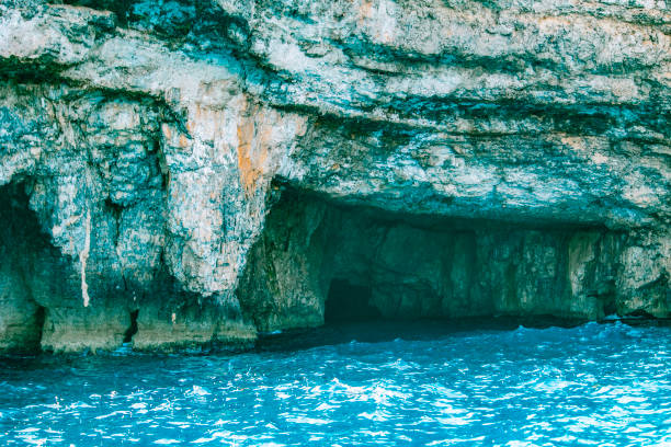Seaside cave with rugged rocky cliffs and bright blue ocean water, creating natural and mysterious coastal landscape.