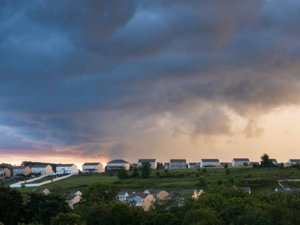 Dramatic thunderstorm clouds hanging over a US residential neighborhood with bright gap in the sky on a summer evening.